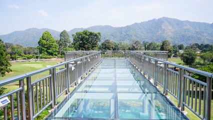 An outdoor bridge with glass floor and stainless railing, sky walk at landscape with green forest.View in vajiralongkorn dam , Kanchanaburi Province,Thailand.