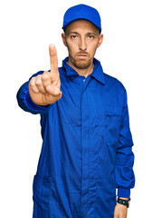 Bald man with beard wearing builder jumpsuit uniform pointing with finger up and angry expression, showing no gesture