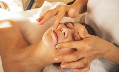 masseur does facial massage, spa procedures, cosmetology facials, face-building massage - obrazy, fototapety, plakaty