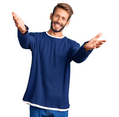 Handsome blond man with beard wearing casual sweater looking at the camera smiling with open arms for hug. cheerful expression embracing happiness.
