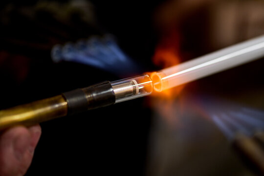neon glass blower using fire to melt electrode to neon glass tube