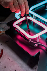 Neon Glass Blower painting on blackout to neon sign