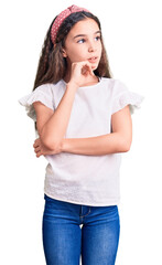 Cute hispanic child girl wearing casual white tshirt with hand on chin thinking about question, pensive expression. smiling with thoughtful face. doubt concept.