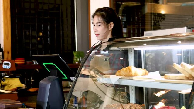 Asian retail small business owner female taking customer order using modern POS purchasing order system machine making selling transaction standing in counter, barista waitress worker happy smiling