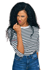 Middle age african american woman wearing casual clothes angry and mad raising fist frustrated and furious while shouting with anger. rage and aggressive concept.