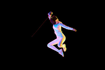 Self-defense skills. Although sportive, fencing skills can represent the broader theme of self-defense. Female athlete in motion, training over black background in neon. Concept of sport, competition