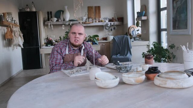 a young man with congenital mental disabilities is engaged in clay modeling sitting at home at a large table.