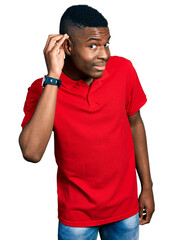 Young african american man wearing casual red t shirt smiling with hand over ear listening an hearing to rumor or gossip. deafness concept.