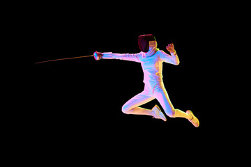 A fencer in full gear lunging with precision, isolated on black background in neon. Female athlete...
