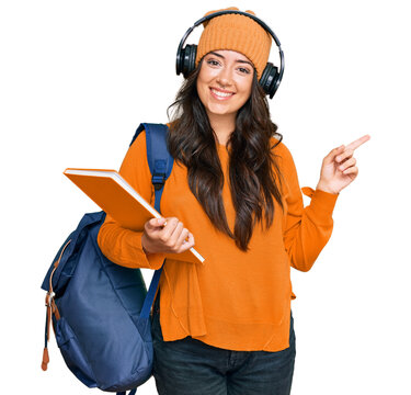 Beautiful brunette young woman wearing student backpack and holding books smiling happy pointing with hand and finger to the side