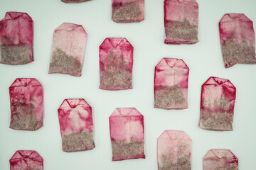 Used pink tea bags are dried, pattern on white background. Sorting waste at home, recycling,...