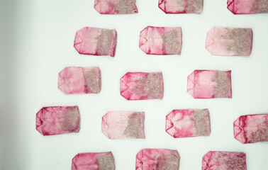 Used pink tea bags are dried, pattern on white background. Sorting waste at home, recycling,...