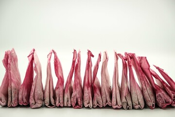Used pink tea bags are dried in a row on white background. Sorting waste at home, recycling,...