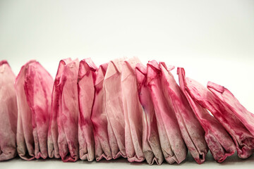 Used pink tea bags are dried in a row on white background. Sorting waste at home, recycling,...