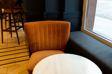 Modern restaurant interior background. An empty table and chair in a restaurant. A cozy soft orange armchair