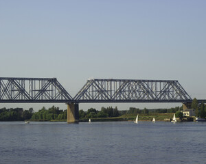 Fototapeta premium A huge beautiful railway bridge over the Volga River, a navigable span. Sailing boats sail along the river.