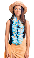 Young beautiful latin girl wearing hawaiian lei and summer hat puffing cheeks with funny face....