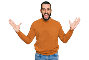 Young man with beard wearing casual winter sweater celebrating victory with happy smile and winner expression with raised hands