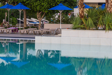 Seascape. Deck chairs and umbrellas by the pool are reflected in the water.