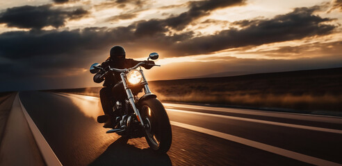 motorcyclist travels at sunset along the road on a chopper.