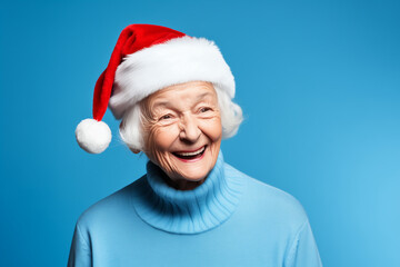 elderly woman smile in red Christmas santa hat, isolated on blue background