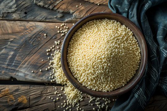 couscous groat raw in bowl on wooden countertop top view