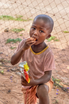 hungry african child in the village eating biscuits and maize snacks