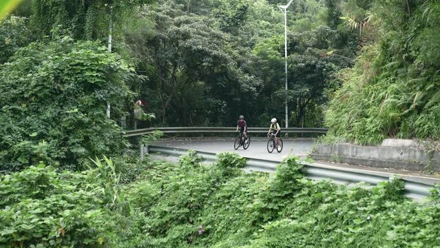 two female cyclists training on slope of rural road, slow motion