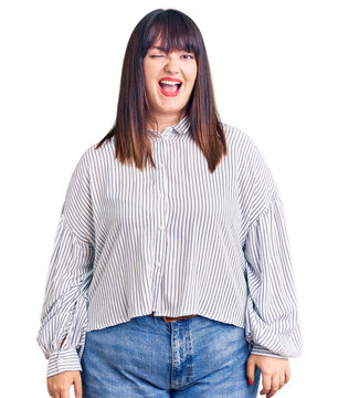 Young plus size woman wearing casual clothes winking looking at the camera with sexy expression, cheerful and happy face.