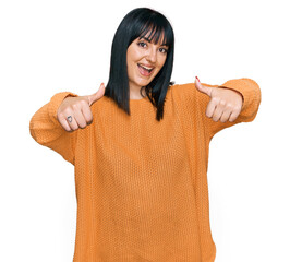 Young hispanic woman wearing casual clothes approving doing positive gesture with hand, thumbs up smiling and happy for success. winner gesture.