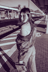 Beautiful girl dressed in 90s style with portable radio receiver in her hands posing on the platform of the train station