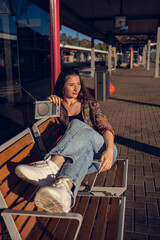 Beautiful girl dressed in 90s style with portable radio receiver in her hands posing on the platform of the train station