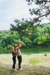 Happy family couple with little newborn son in nature. Happy young mother and father with a child on a walk in the forest. The concept of a happy married couple with a child