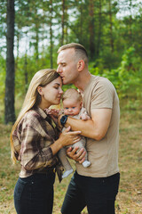 Happy young mother and father with a child on a walk in the park. The concept of a happy married couple with a child. Happy family couple with little newborn son in nature.