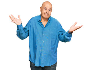 Fototapeta premium Middle age bald man wearing casual clothes clueless and confused expression with arms and hands raised. doubt concept.
