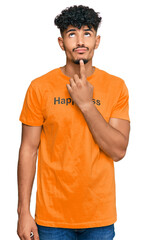 Young arab man wearing tshirt with happiness word message thinking concentrated about doubt with finger on chin and looking up wondering