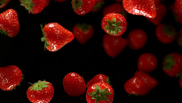 Super Slow Motion of Strawberries Isolated on Black Background. Filmed on High Speed Cinema Camera, 1000 fps. Speed Ramp Effect.