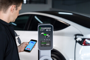 Young man travel with EV electric car to shopping center parking lot charging in downtown city...