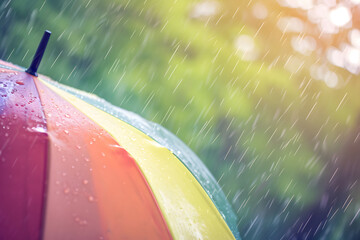 Farbenfroher Schutz im Regen: Ein Regenschirm in Regenbogenfarben, eine lebendige Szene, die den Schutz vor Nässe mit einem Hauch von Farbenpracht vereint.
