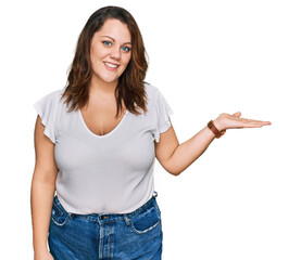 Young plus size woman wearing casual white t shirt smiling cheerful presenting and pointing with...