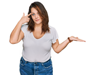 Young plus size woman wearing casual white t shirt confused and annoyed with open palm showing copy space and pointing finger to forehead. think about it.