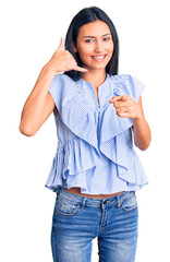 Young beautiful latin girl wearing casual clothes smiling doing talking on the telephone gesture...