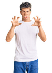 Young handsome man wearing casual white tshirt smiling funny doing claw gesture as cat, aggressive...