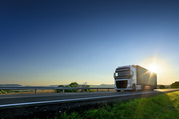 Large Transportation Truck on a highway road through the countryside at sunset - obrazy, fototapety, plakaty