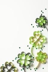 Abstract St Patrick Day background with paper clover leaves and confetti on white table. Top view. Flat lay.