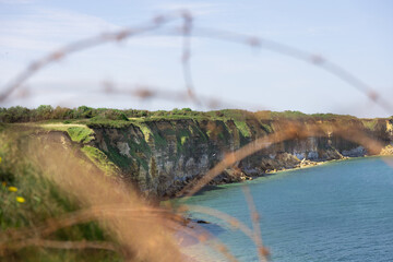 The Cliffs of Pointe Du Hoc through a barbed wire fence