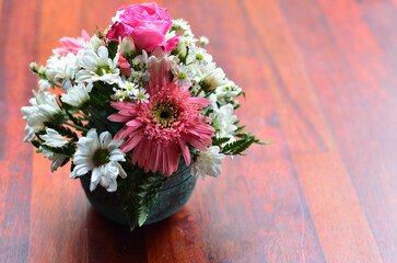 red and white flowers in a vase on a maroon brown table