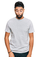 Young man with beard wearing casual grey tshirt making fish face with lips, crazy and comical gesture. funny expression.