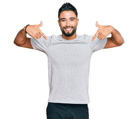 Young man with beard wearing casual grey tshirt looking confident with smile on face, pointing oneself with fingers proud and happy.