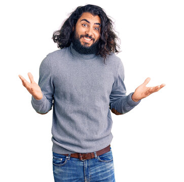 Young arab man wearing casual clothes clueless and confused expression with arms and hands raised. doubt concept.
